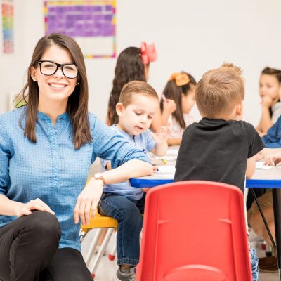 Portrait of a gorgeous Hispanic preschool teacher loving her job and having fun with her pupils